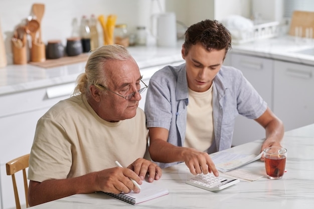 Premium Photo Grandson Helping Grandfather To Calculate Expenses
